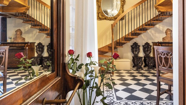 A grand staircase with wooden railings and a checkered floor. - Saint George's House Apartments & SPA (Pachino)
