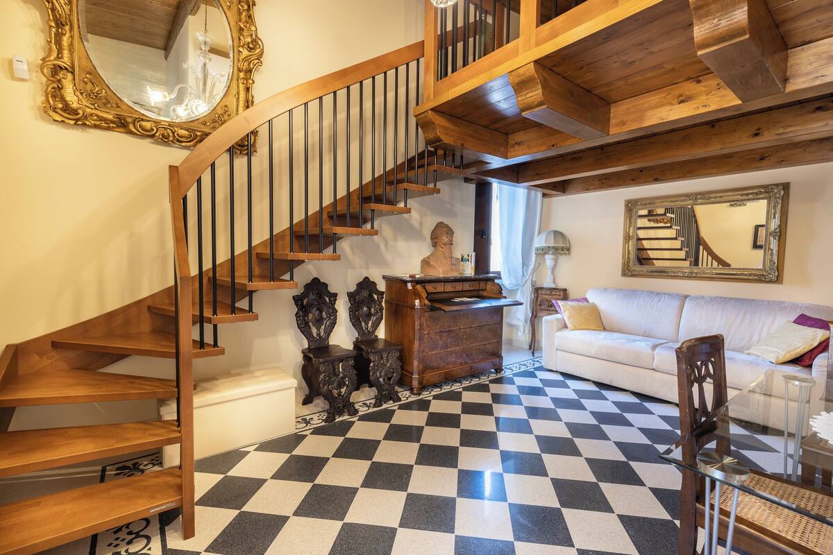 A staircase with wooden railings and a black and white checkered floor.