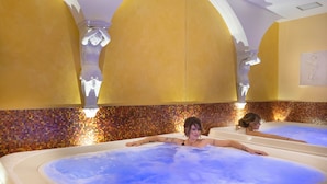 A spa area with two hot tubs, tiled walls, and decorative columns. - Saint George's House Apartments & SPA (Pachino)