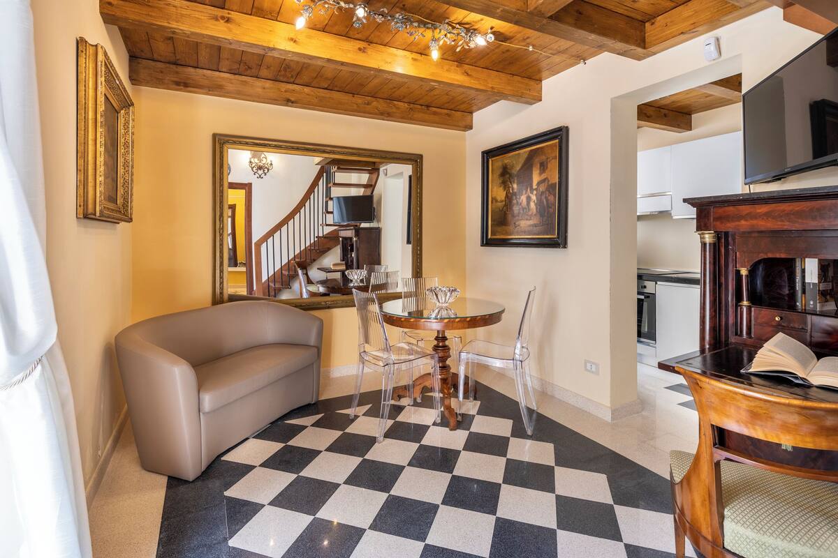 A living room with a checkered floor, a sofa, a dining table with chairs, a TV, and a fireplace.
