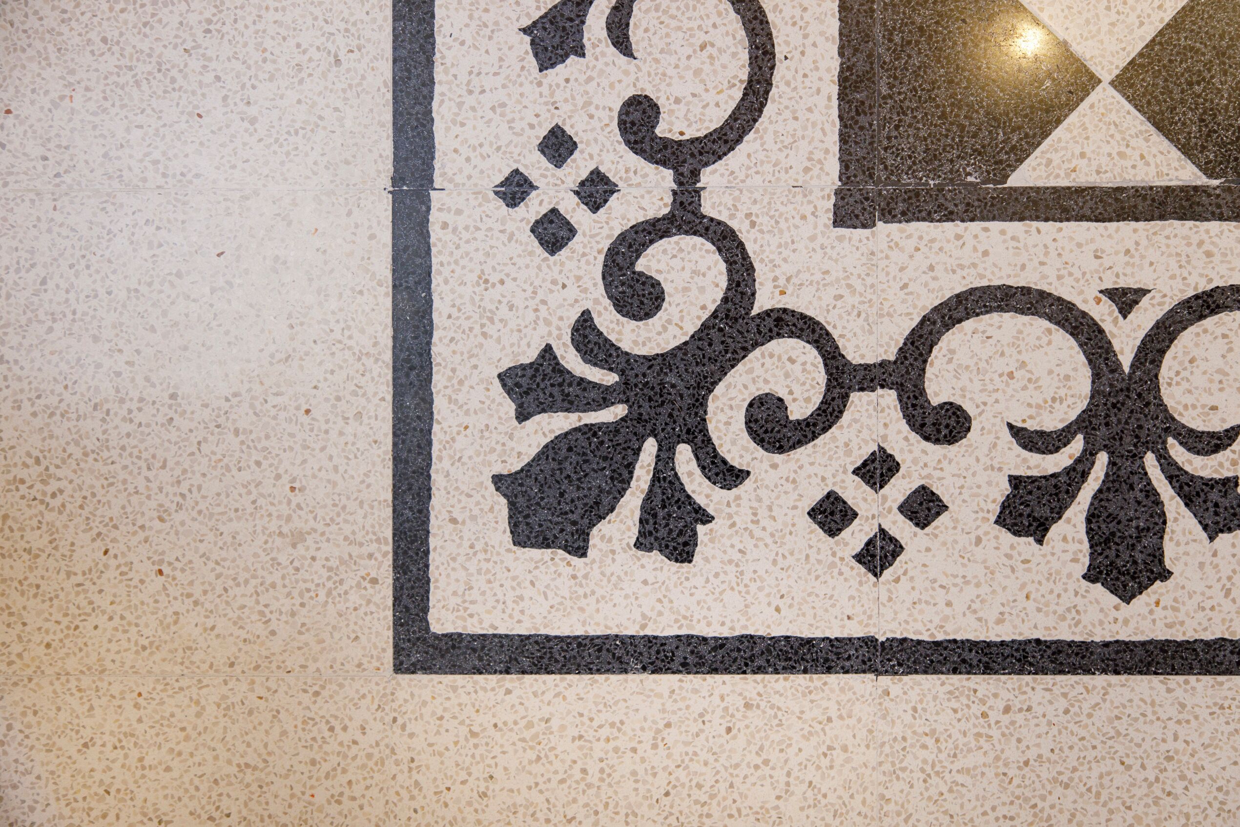 Ein detailliertes Fliesenmuster mit einem zentralen geometrischen Design und dekorativen Elementen.