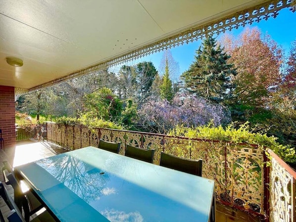 An outdoor patio with a table and chairs, surrounded by a decorative fence and trees.