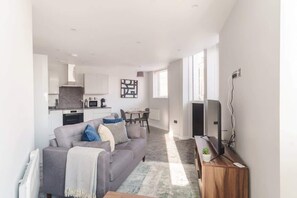A modern living room with a grey sofa, a coffee table, and a TV on a wooden stand.