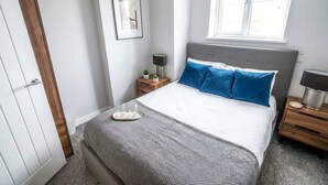 Una camera da letto con un letto, comodini, una finestra e una porta.