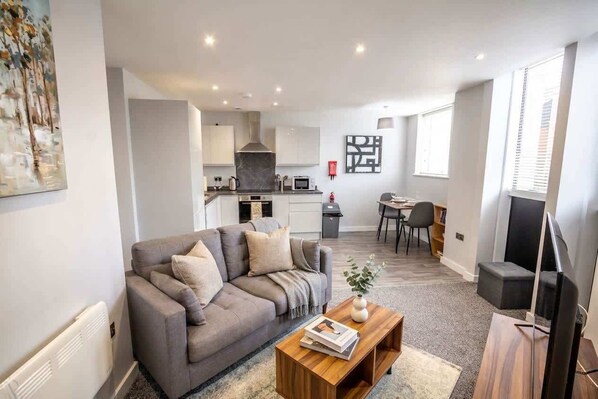 A modern living room with a sofa, coffee table, and a flat-screen TV.