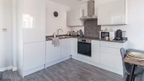Una cucina moderna con mobili bianchi, forno integrato, microonde e macchina del caffè.