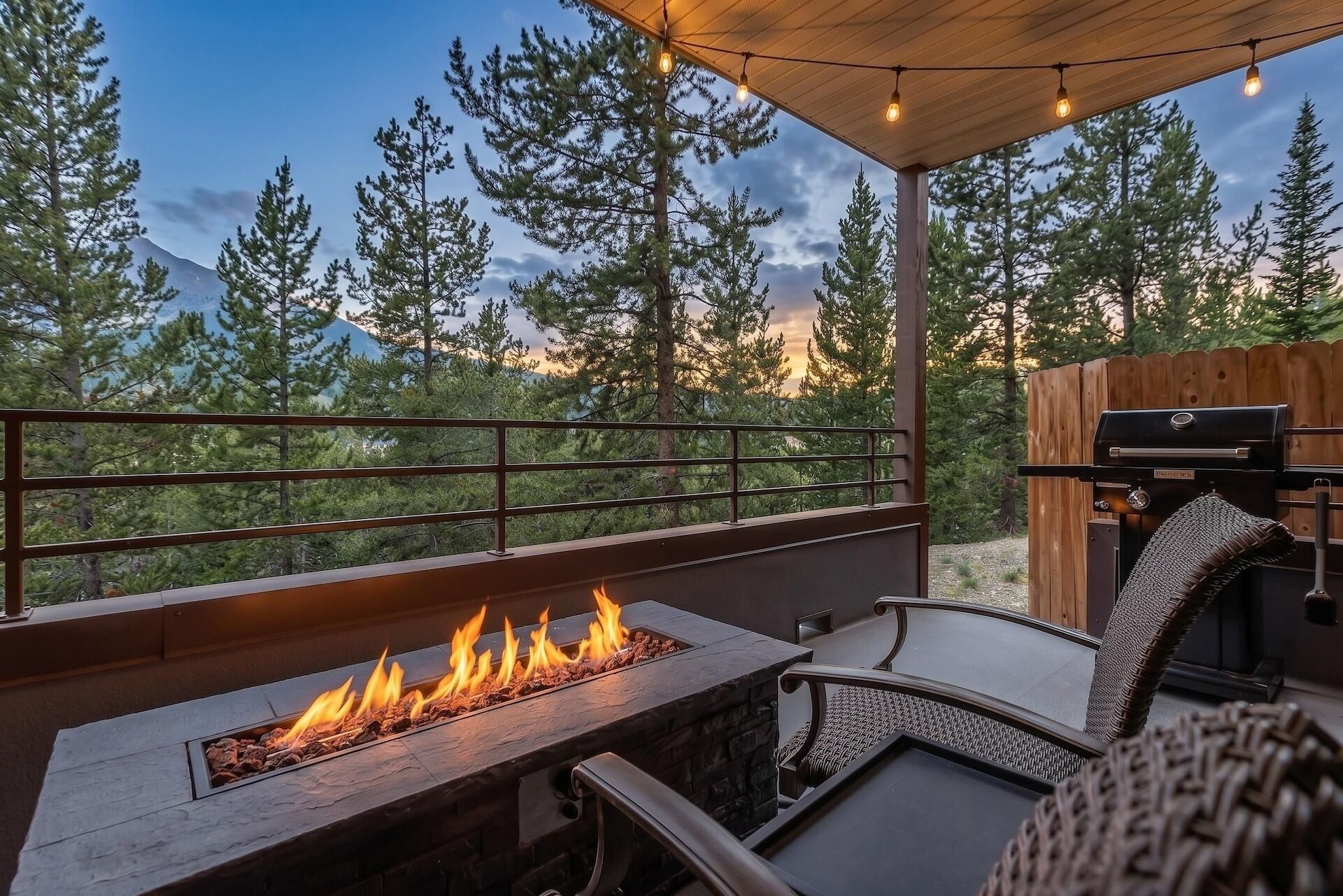 An outdoor patio with a fire feature, seating, and a grill.