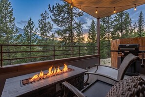 Une terrasse extérieure dotée d’un foyer, de sièges et d’un barbecue.