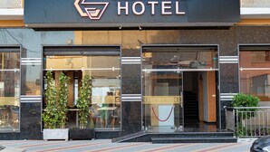 Das Außengelände des Golden Sunset Hotels mit auffälliger Beschilderung, großen Fenstern und einer roten Absperrschnur.