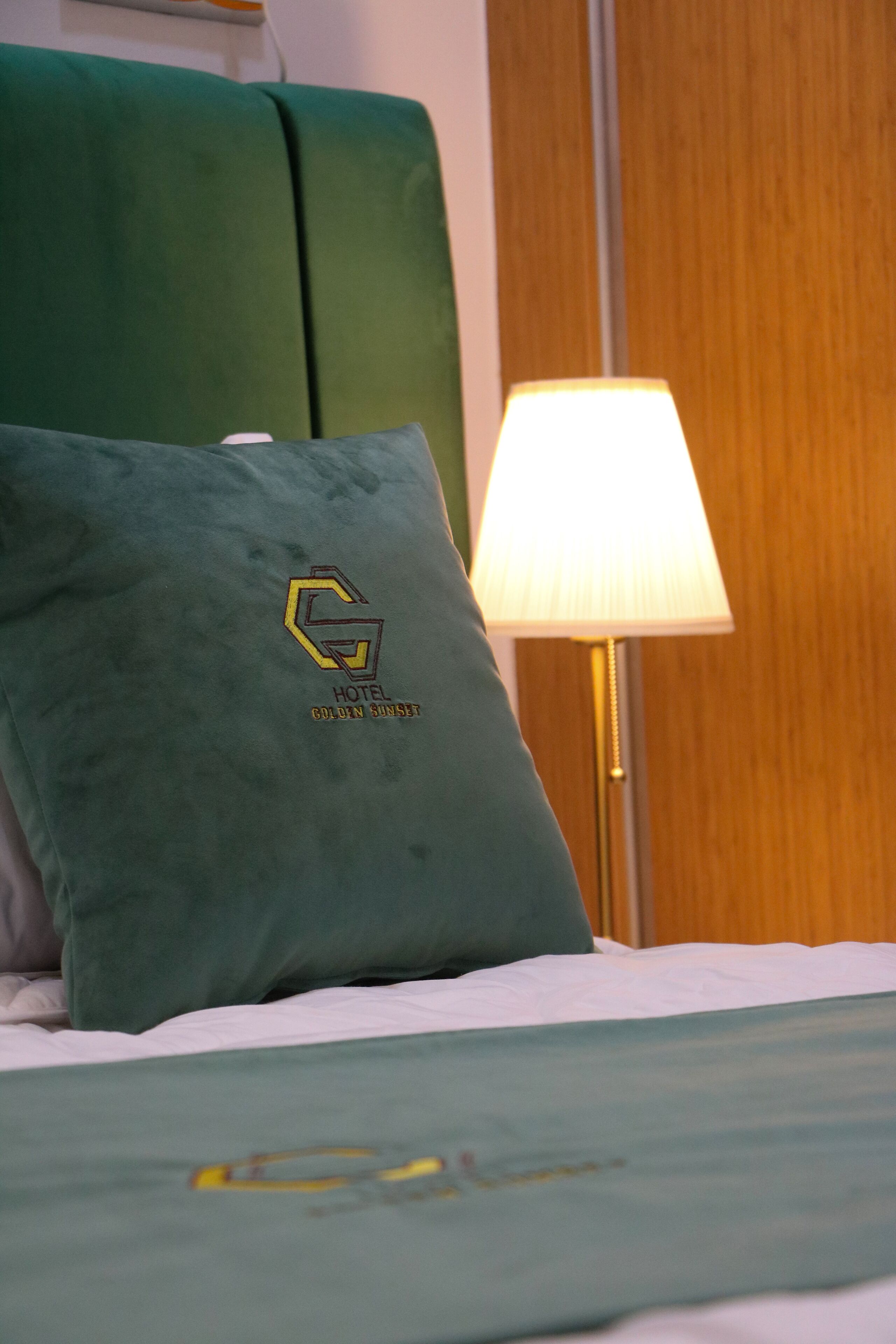 A bed with a green pillow and a lamp.