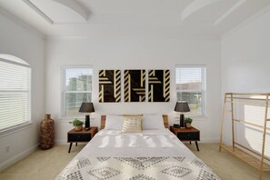 A bedroom with a large bed, two nightstands, a wooden side table, a wall-mounted lamp, a decorative vase, and a window with blinds. - Spacious Pet-Friendly: Quiet, 2 Kitchens, 2 Living Rooms (Round Rock)