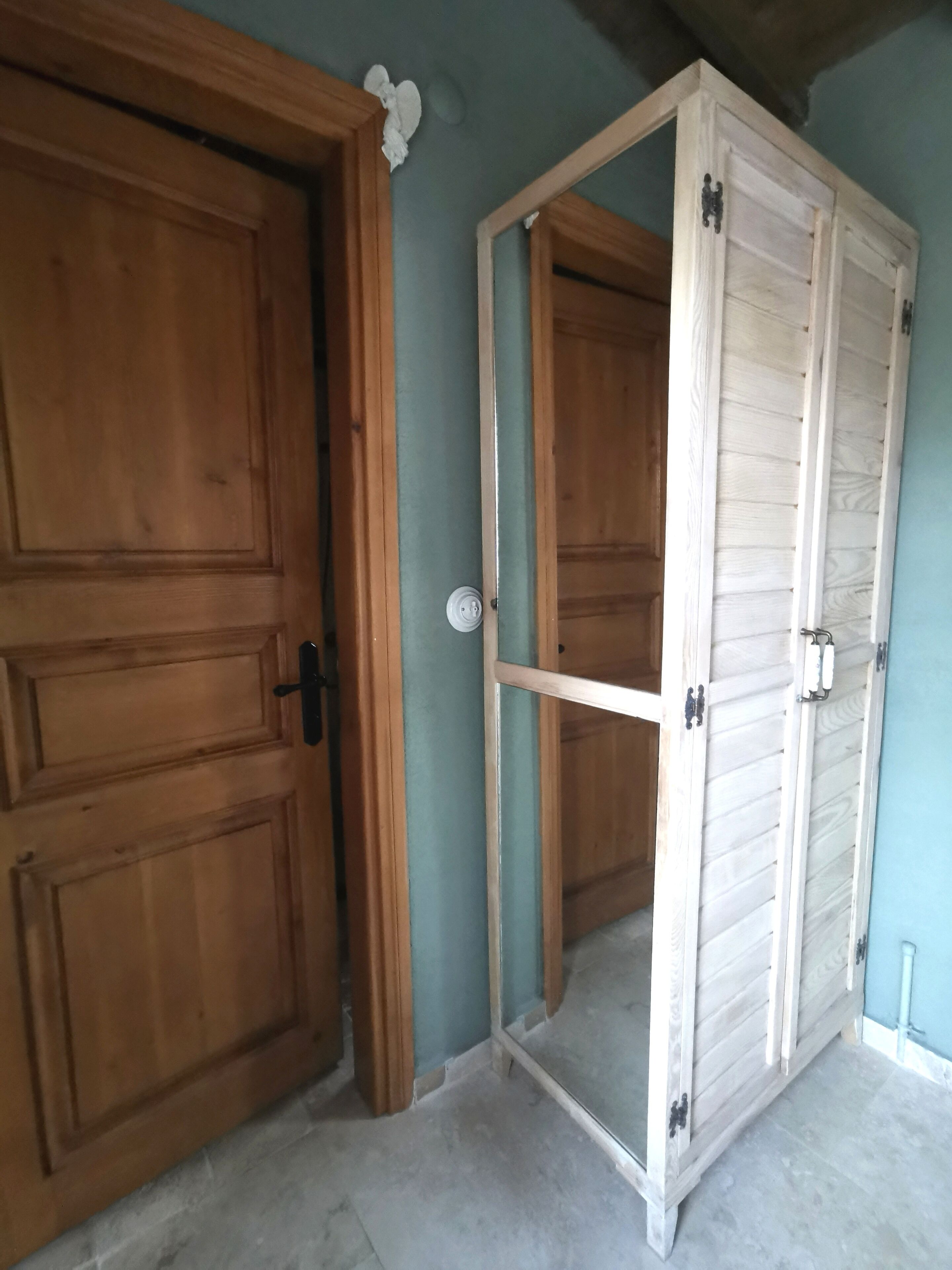 Una habitación con puerta de madera y un armario con puerta de espejo.