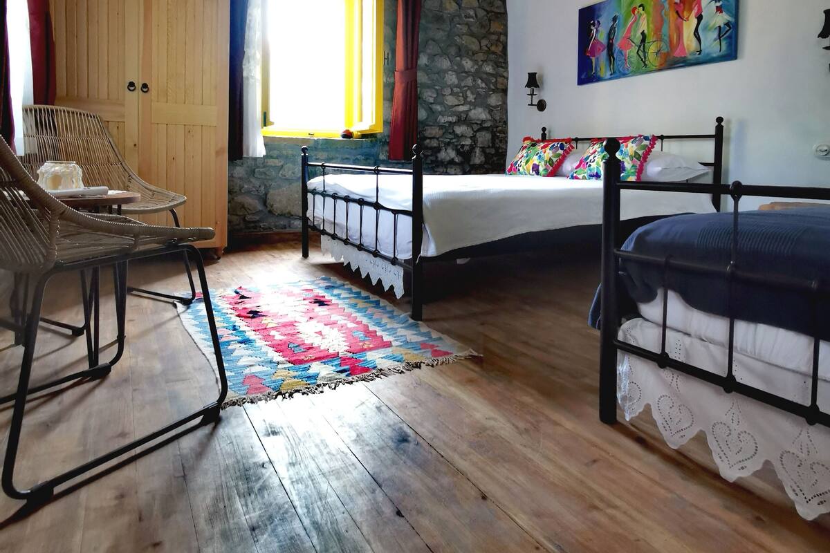 A bedroom with a wooden ceiling, a bed, a chair, a wardrobe, a window, and a painting.