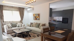 Un salon moderne comprenant un canapé, une table basse et une table à manger. Il y a également un coin cuisine avec un évier et une cuisinière.
