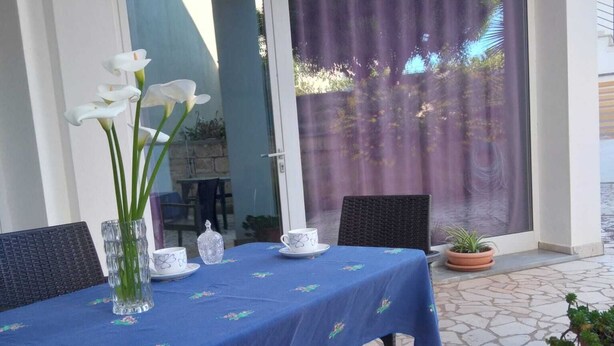 A table set outdoors with a blue tablecloth, white flowers, and a teapot. - Vignamarino House (Alessano)