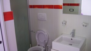 A bathroom with a toilet, sink, and mirror. - Vignamarino House (Alessano)