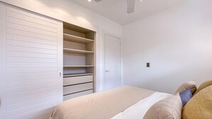 A bedroom with a bed, a closet with sliding doors, a ceiling fan, and a light switch on the wall. - Luxury 3 bedroom Apartment at the beach (Punta Cana)
