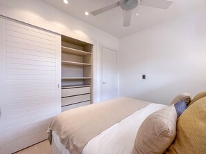 Un dormitorio con una cama, un armario con puertas correderas, un ventilador de techo e interruptor de luz en la pared.