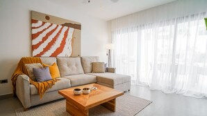 A modern living room with a sofa, coffee table, and a large abstract painting. - Luxury 3 bedroom Apartment at the beach (Punta Cana)