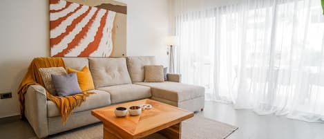A modern living room with a sofa, coffee table, and a large abstract painting.