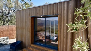 Ein modernes Holzgebäude mit Glastür und Stufen, die zu einer Terrasse führen.