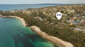 An aerial view of a coastal town with a beach, residential areas, and a mix of houses and buildings. - Minerva Beach House by Experience Jervis Bay (Vincentia)