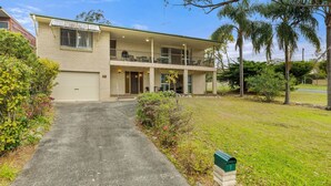 A two-story building with a covered front porch, a garage, and a small front yard with a mailbox. - Minerva Beach House by Experience Jervis Bay (Vincentia)