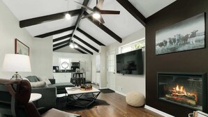 Una sala de estar moderna con chimenea, suelo de madera y un comedor con mesa y sillas.