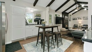 Una cocina moderna con armarios blancos, una mesa de madera oscura y taburetes de bar.