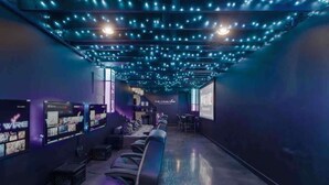 A gaming lounge with multiple gaming stations, comfortable seating, and a modern ceiling design. - Calling All Gamers_Sleeps 10_Near MCI_Fun for All (Platte City)