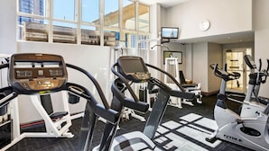 Un gimnasio con cintas de correr, bicicletas estáticas y máquinas de pesas.