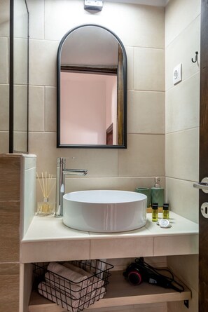 A modern bathroom with a round white sink, a large mirror, and a towel rack. - Joel Living Collection - Rustic Villa (Chania)