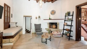 Ein gemütliches Wohnzimmer mit einer Steinsitzbank, Kamin, Holzboden und Bücherregal.