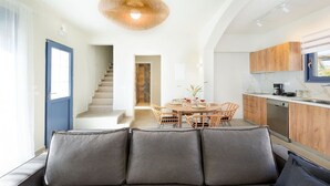 Eine moderne Küche mit Holzausstattung, eine Essecke mit rundem Tisch und eine Treppe, die eine weitere Ebene hinaufführt.