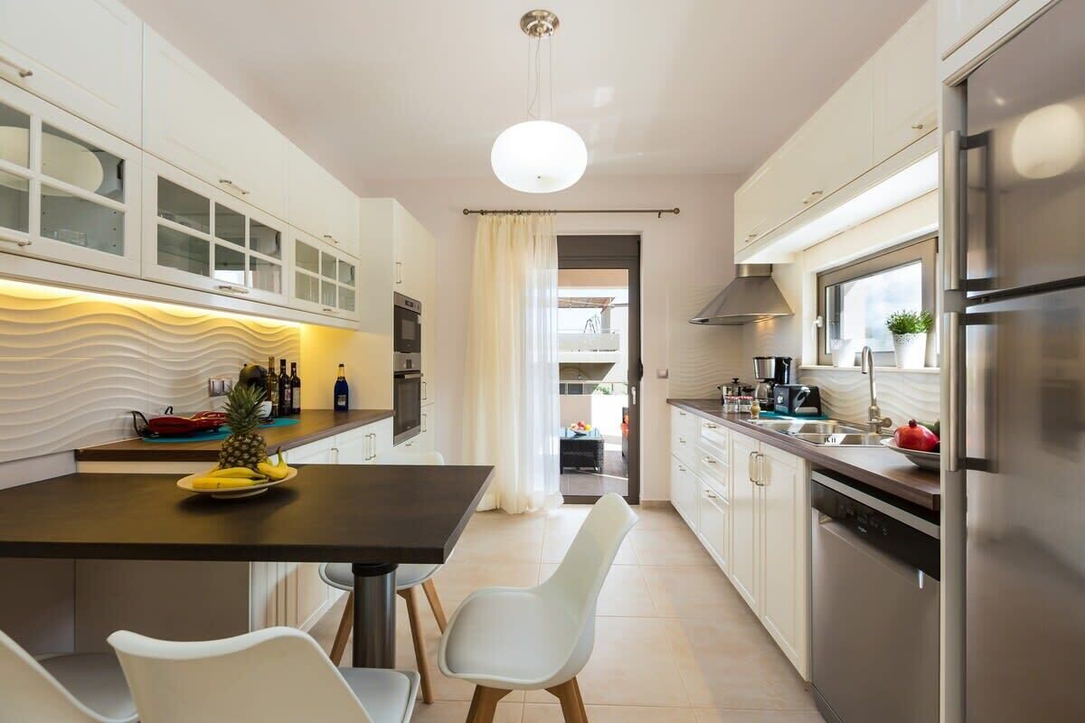 Een moderne keuken met witte kasten, een zwart aanrecht en een roestvrijstalen koelkast.