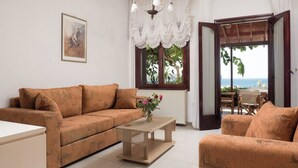 Una sala de estar con un sofá, una mesa de centro y vista al mar a través de una puerta abierta.