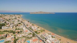 A coastal town with a beach, residential buildings, and a small island in the distance.