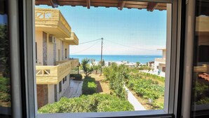 A view from a window overlooking a residential area with a clear sky, a distant view of the sea, and a well-maintained garden. - Romantic Corner | Theofilos Sea View (Stalos)