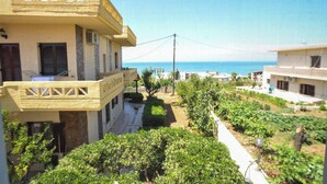 A multi-story building with balconies overlooking a garden and the sea. - Romantic Corner | Theofilos Sea View (Stalos)