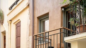 A two-story building with a balcony, a door with a sign, and potted plants. - Casa Sorvolou Boutique House (Chania)