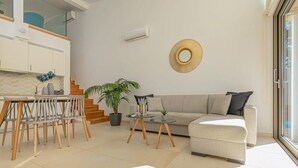 En moderne stue med sofa, sofabord og spiseområde med stole.