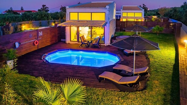 Ett modernt hus med en swimmingpool, utomhusmöbler och en väl upplyst uteplats.