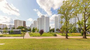 A residential area with modern apartment buildings, a grassy park area, and a paved walkway.