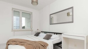 A bedroom with a bed, bedside table, and a large mirror.