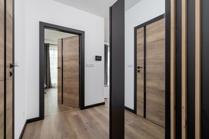 Ein Gang mit Holzboden und schwarzen Türrahmen.