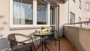 A balcony with a round table, two wicker chairs, and a potted plant.