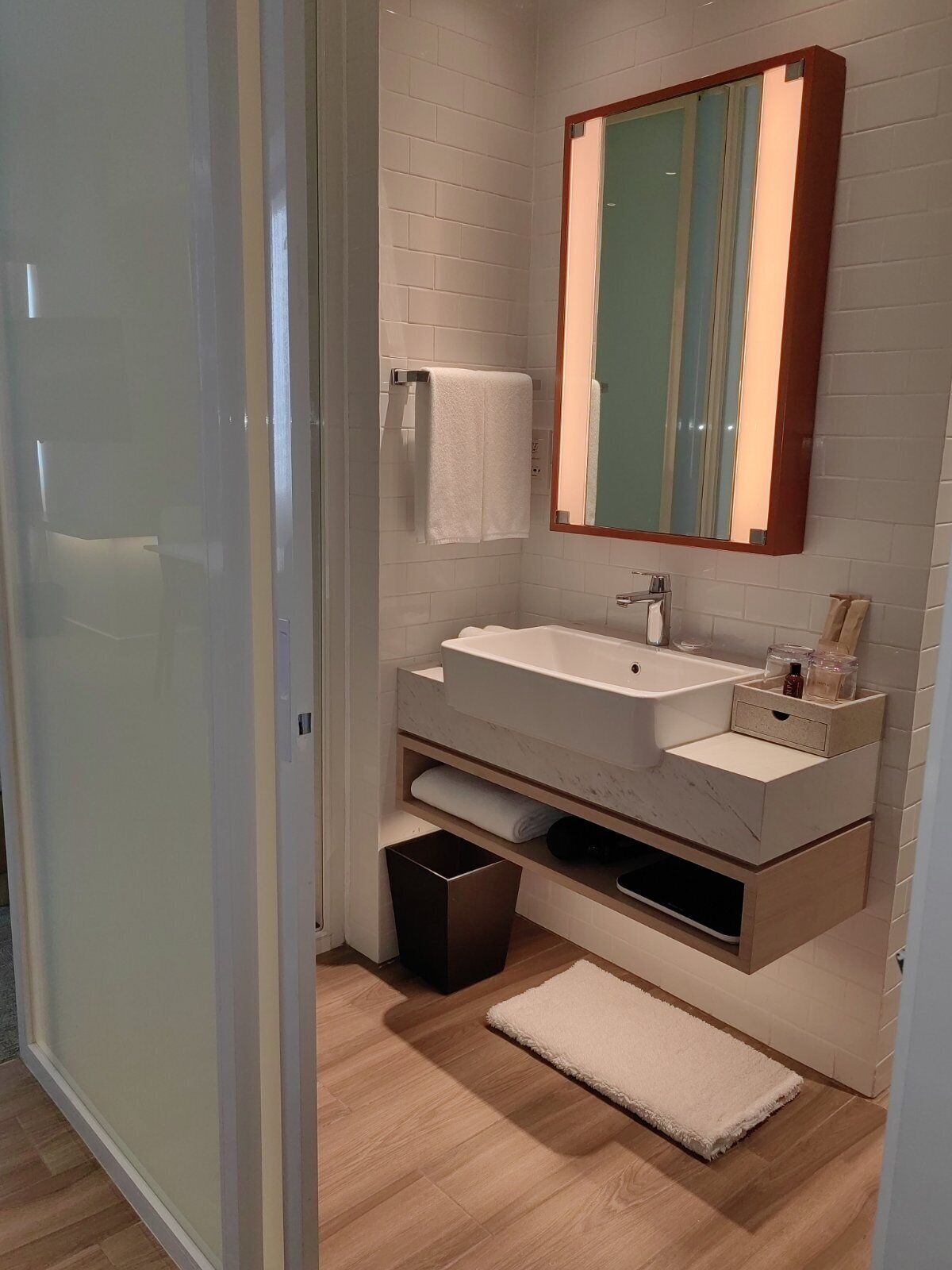 Une salle de bain moderne avec un lavabo blanc, un miroir et un porte-serviettes.