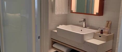 A modern bathroom with a white sink, mirror, and towel rack.