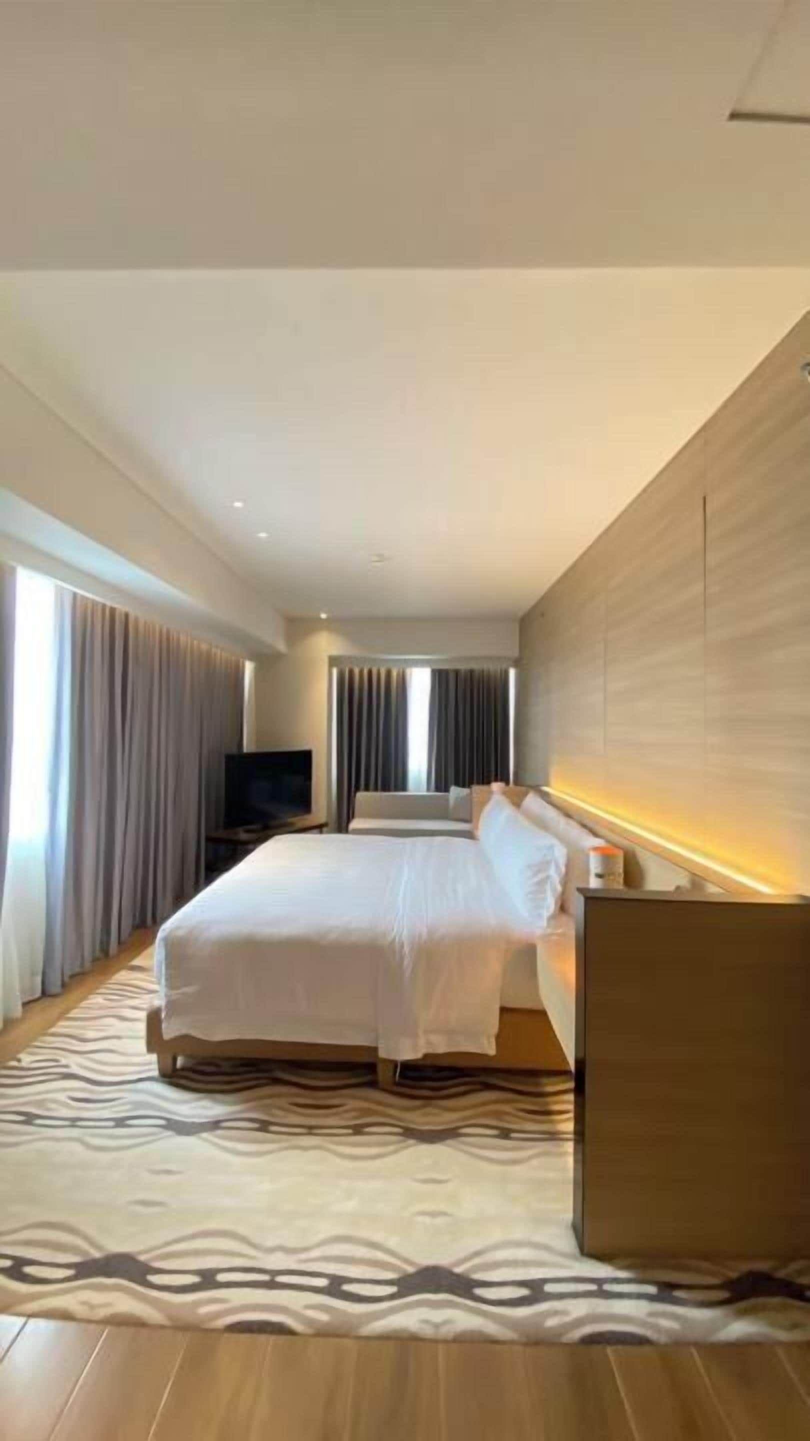 Een moderne hotelkamer met een groot bed, een flatscreen televisie en een houten accentmuur.