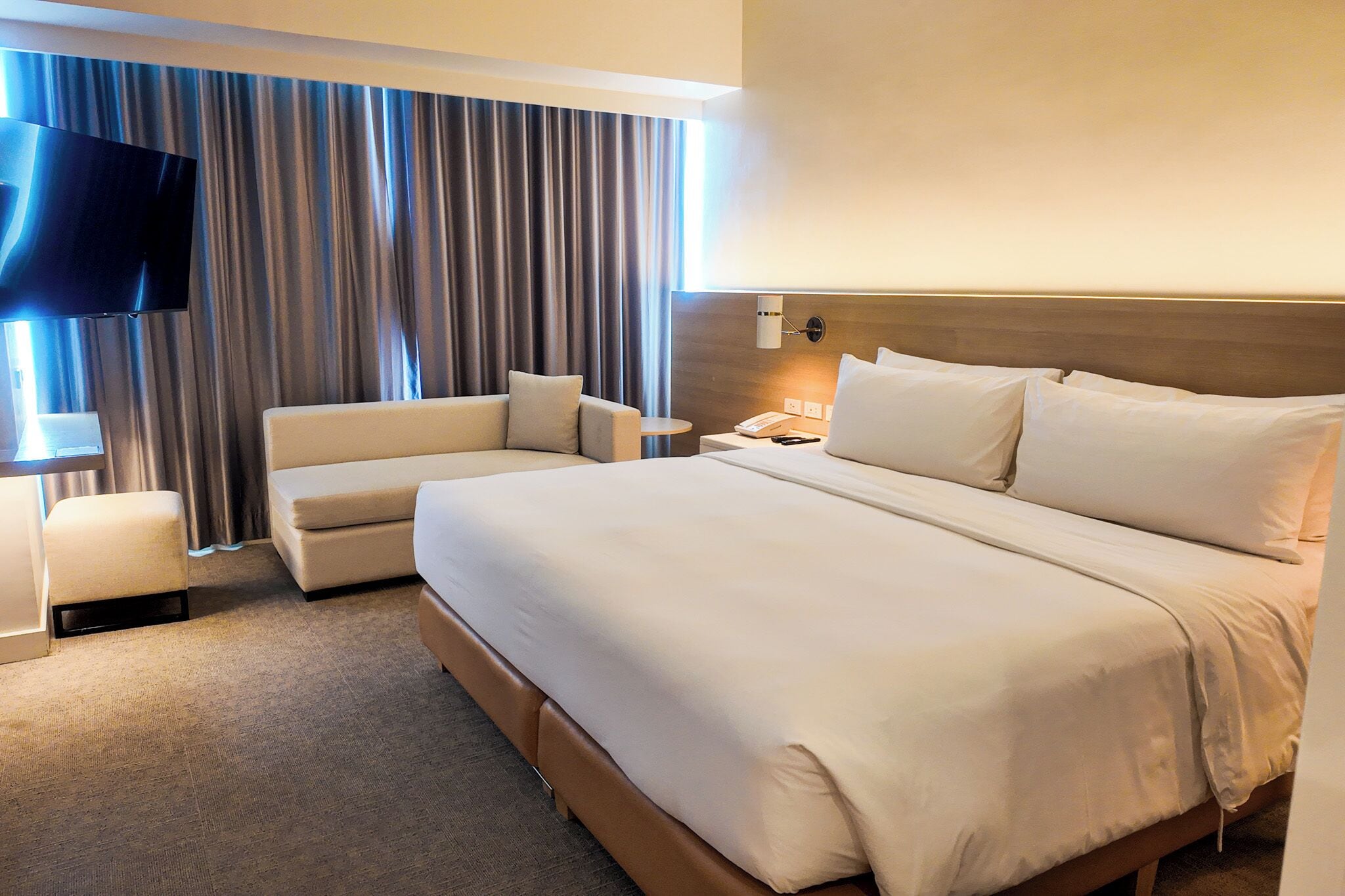 Une chambre d’hôtel avec un grand lit, un canapé, une télévision et une lampe.